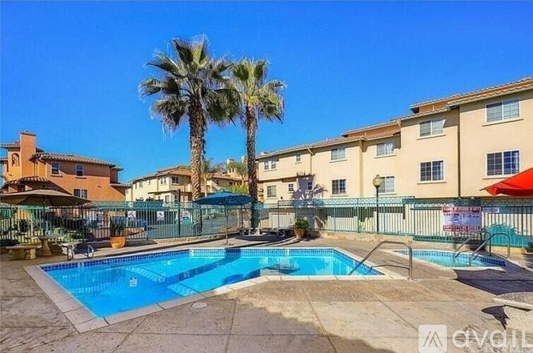 A pool surrounded by a fence with a palm tree in the background.