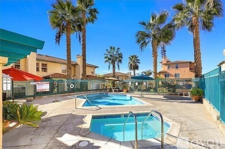 A pool surrounded by palm trees and a fence.