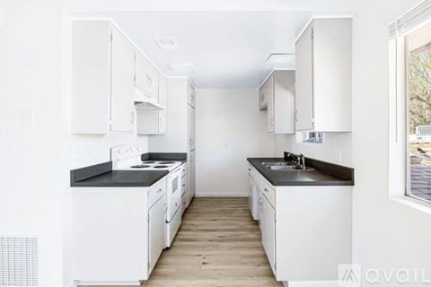 A kitchen with white cabinets and black countertops.