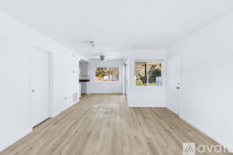 A spacious room with wooden flooring and white walls.