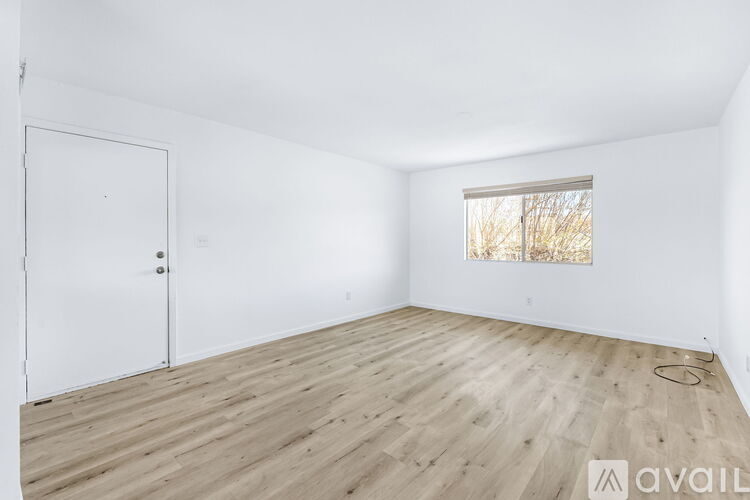 A room with a white door and a window with a view of trees outside.