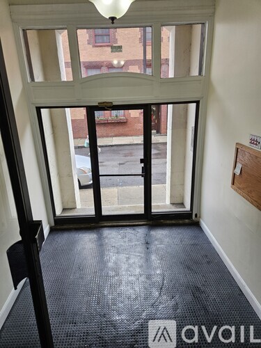 A hallway with a black floor and white walls leading to a door.