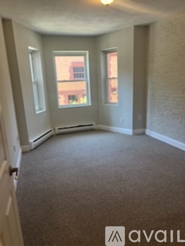 A carpeted room with a window and a door.