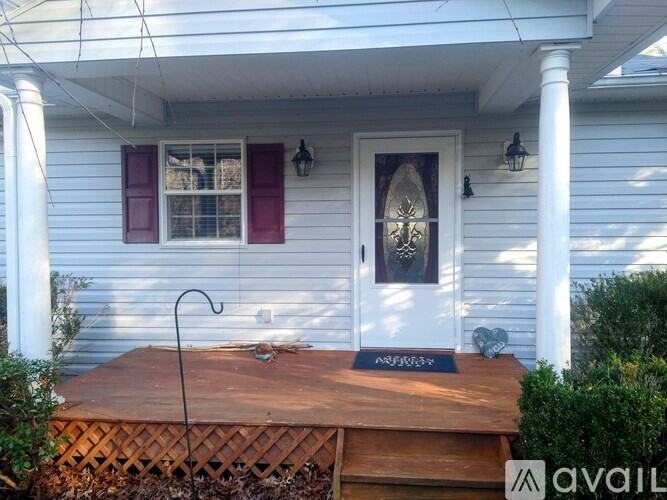 A white house with a wooden porch and a window with red shutters.