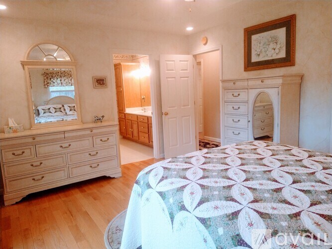 A bedroom with a large bed and a dresser with a mirror.