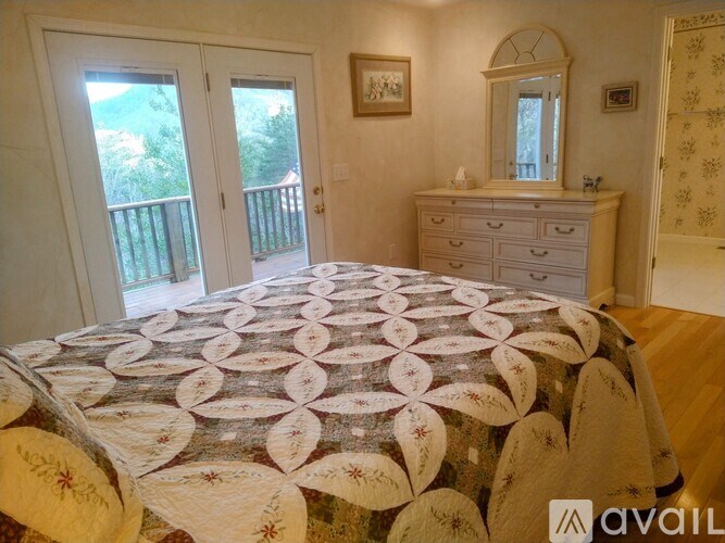 A bedroom with a bed, dresser, and mirror.
