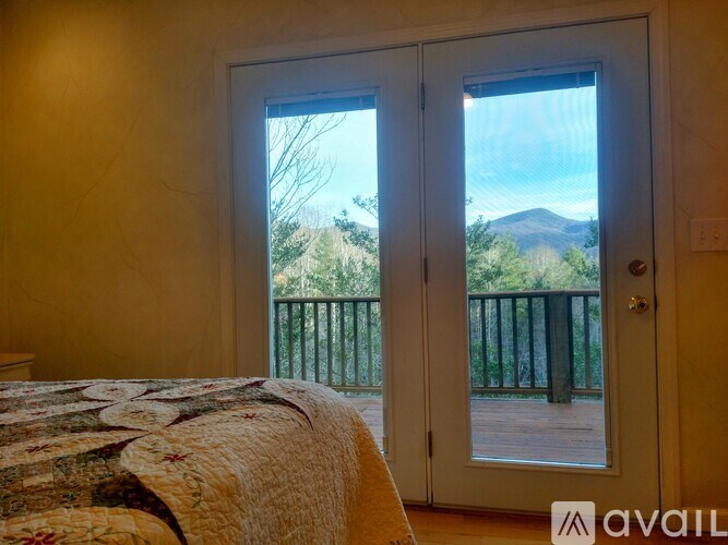 A bedroom with a bed and a view of a mountain through the door.