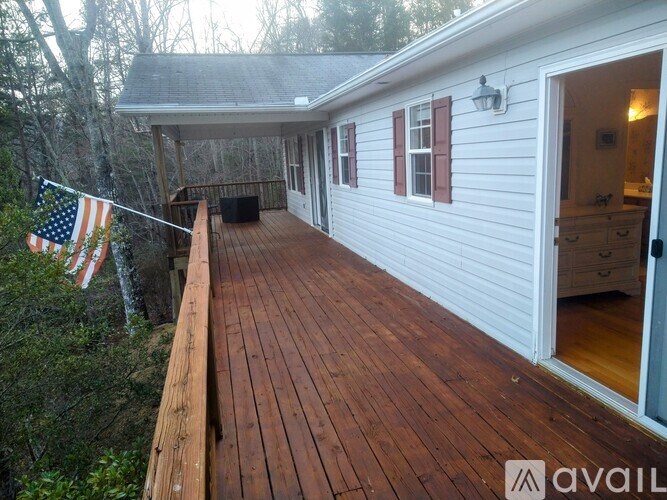 A wooden deck with a flag on a pole and a white house in the background.