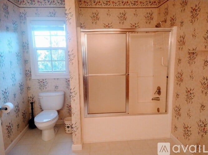 A bathroom with floral wallpaper and a toilet next to a window.