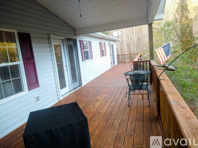 A wooden deck with a black ottoman and a chair with an American flag in the background.