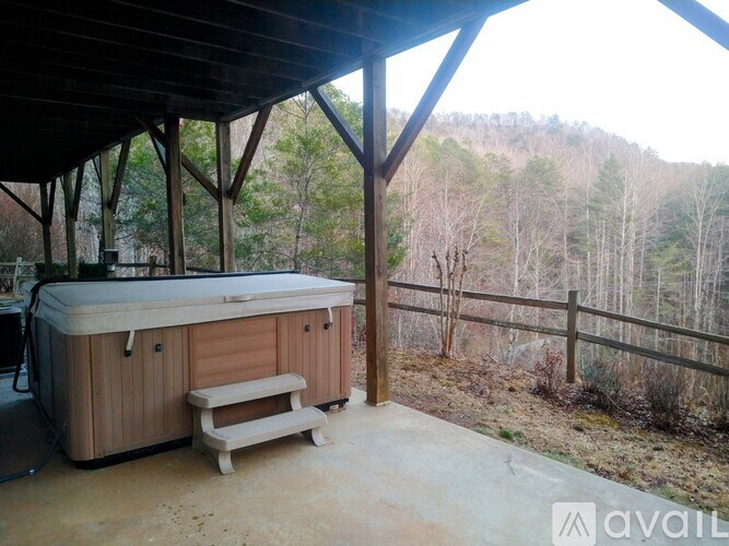 A hot tub sits on a patio with a view of a wooded area.