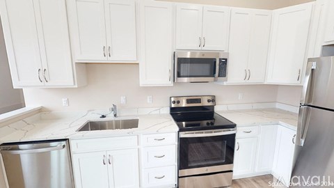 A kitchen with white cabinets and appliances.