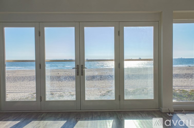 A room with a view of the beach through large windows.