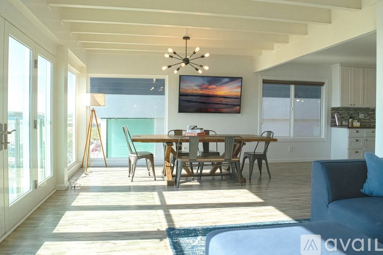 A sunset painting hangs over a dining table in a well-lit room.