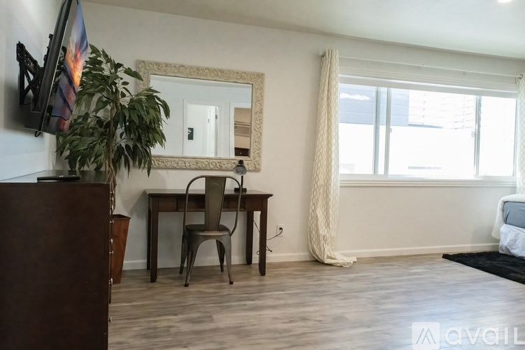 A room with a desk and a chair in front of a large mirror.