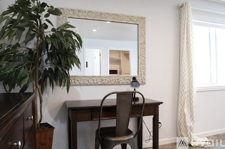 A room with a desk, chair, and a mirror.