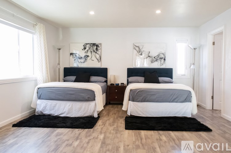 A bedroom with two beds and a rug on the floor.
