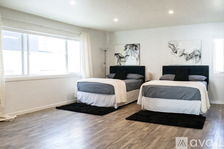Two twin beds in a room with white walls and wooden floors.
