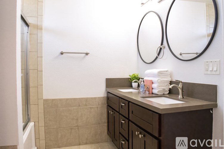 A bathroom with a brown vanity and a mirror above it.