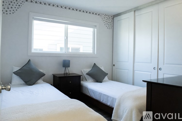 A bedroom with two beds, a nightstand, and a window with blinds.