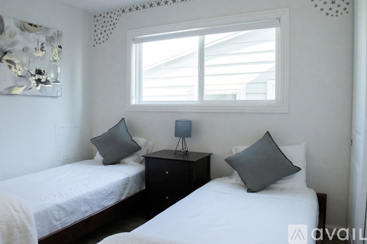 A bedroom with two beds and a nightstand with a lamp.