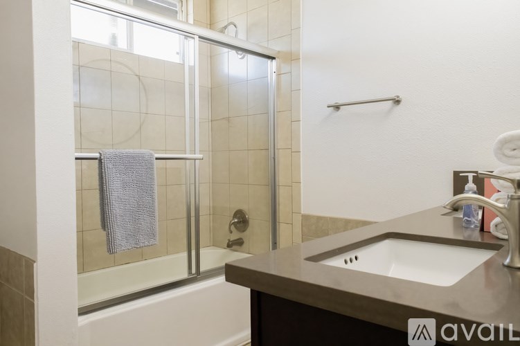 A bathroom with a sink, a towel, and a shower.
