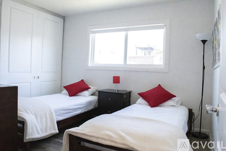 Two beds in a room with white walls and a window.