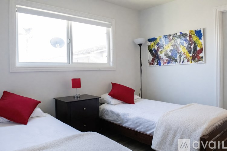 A bedroom with two beds, one of which has a red pillow.