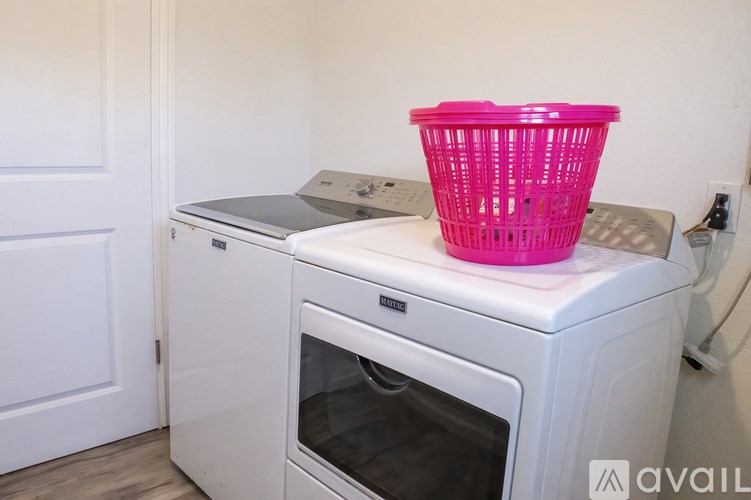 A pink basket is on top of a white dishwasher.