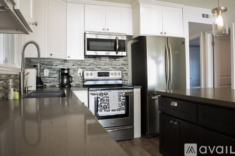 A modern kitchen with a black countertop and stainless steel appliances.