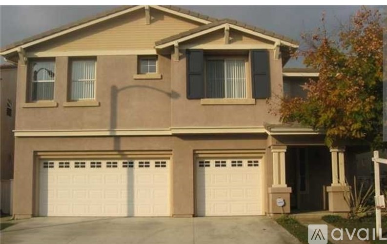 A two-story house with a beige facade and white garage doors.