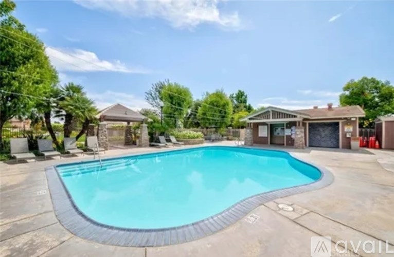 A large outdoor swimming pool surrounded by a concrete patio and residential houses.