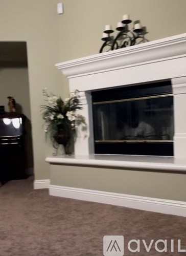 A fireplace with a white mantle and a vase of flowers on the ledge.