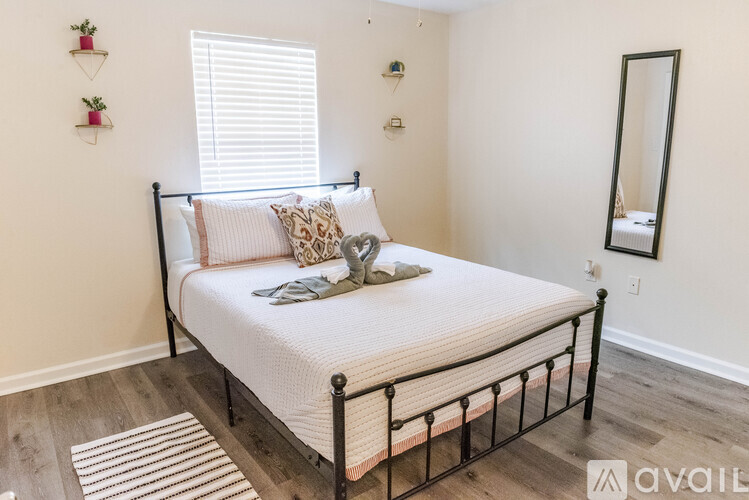 A bedroom with a neatly made bed and a mirror on the wall.
