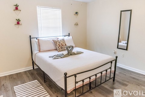 A bedroom with a neatly made bed and a mirror on the wall.