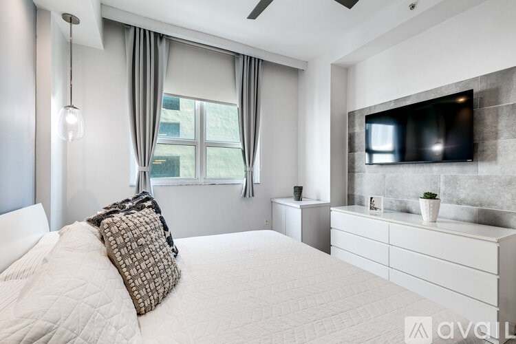 A modern bedroom with a large bed and a flat screen TV mounted on the wall.