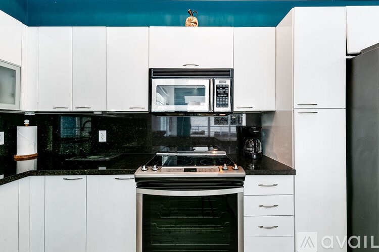 A kitchen with white cabinets and black countertops.