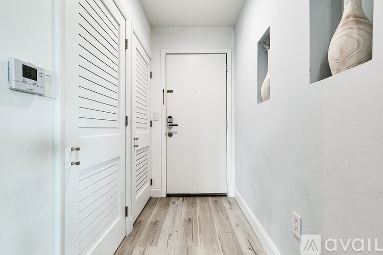 A hallway with a white door and a white wall.