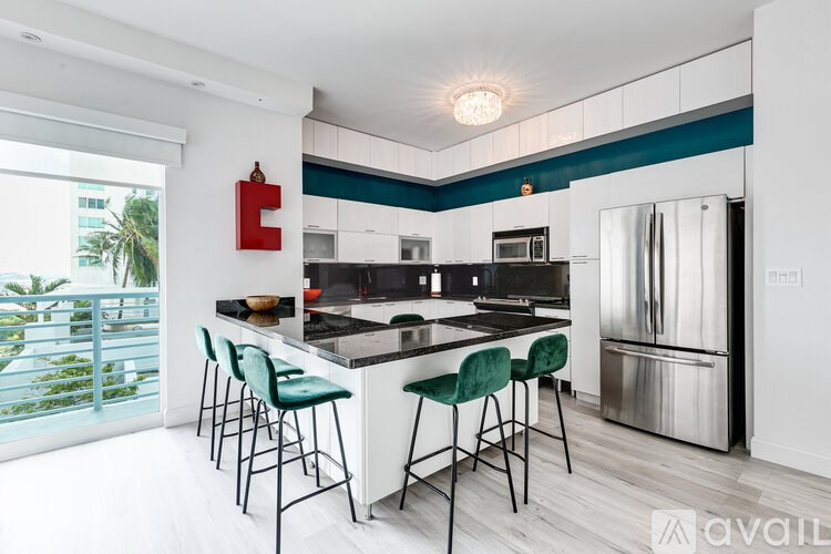A kitchen with a black countertop and green barstools.