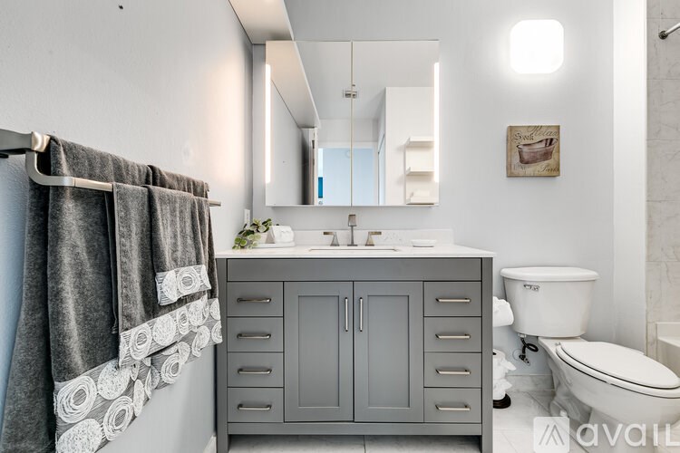 A bathroom with a grey cabinet and a white toilet.