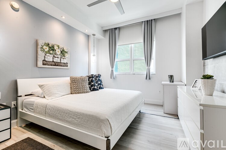 A bedroom with a large bed and a television on the wall.