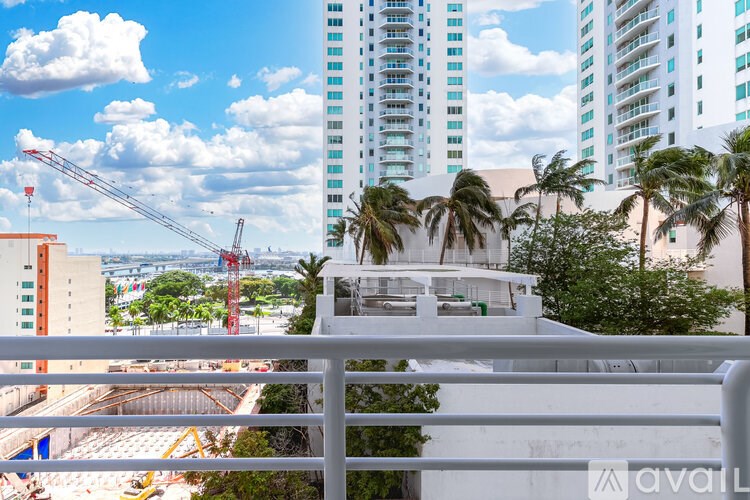 A view from a balcony overlooking a construction site with cranes and buildings in the background.