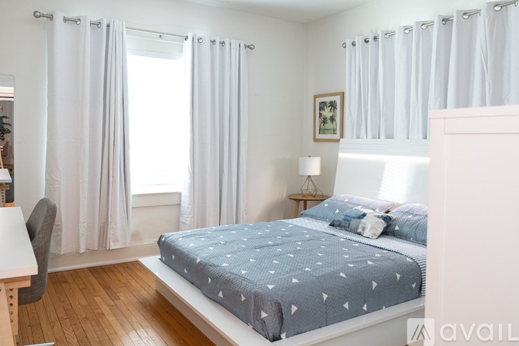 A bedroom with a bed, a chair, and a window with curtains.