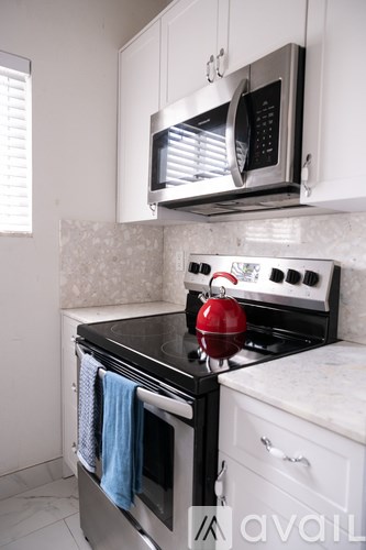 A kitchen with a black stove top oven and a red kettle on it.