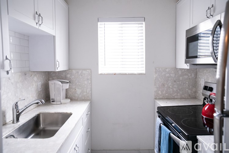 A kitchen with white cabinets and a black stove top.