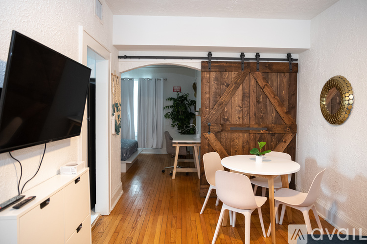A room with a white table and chairs, a flat screen TV, and a wooden door.