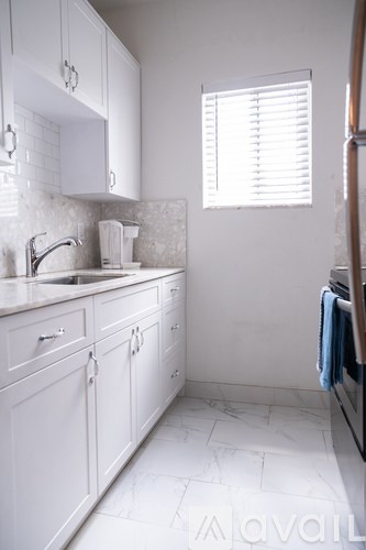 A white kitchen with a sink and a window.