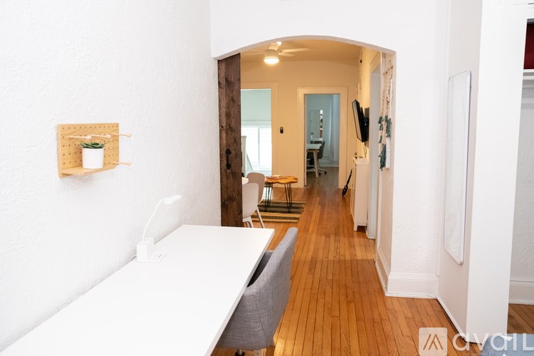 A white couch sits in a hallway with wood floors and white walls.