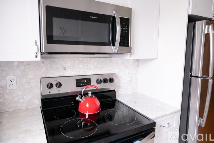 A red kettle is on a black stove.