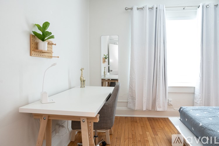 A white desk with a chair and a mirror in a room.